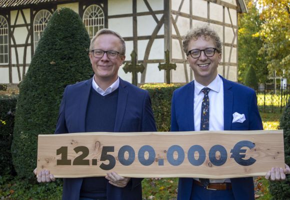 Bundestagsabgeordneter Alexander Bartz überreicht dem Museumsdirektor Dr. Torsten W. Müller einen Scheck über die neue Fördersummer von 12,5 Millionen Euro für das Museumsdorf Cloppenburg.