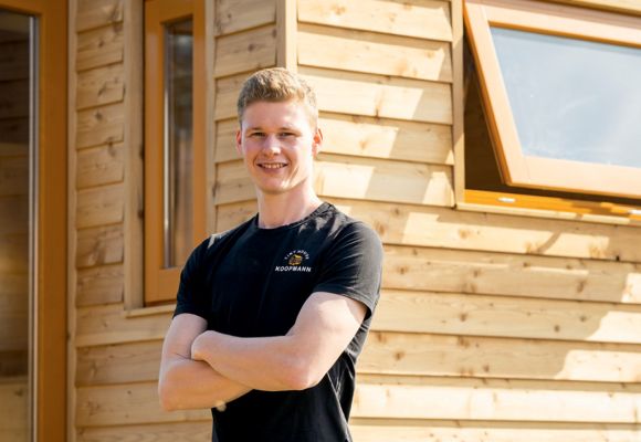Tischlermeister Christian Koopmann steht mit verschränkten Armen vor einem seiner Tiny Houses
